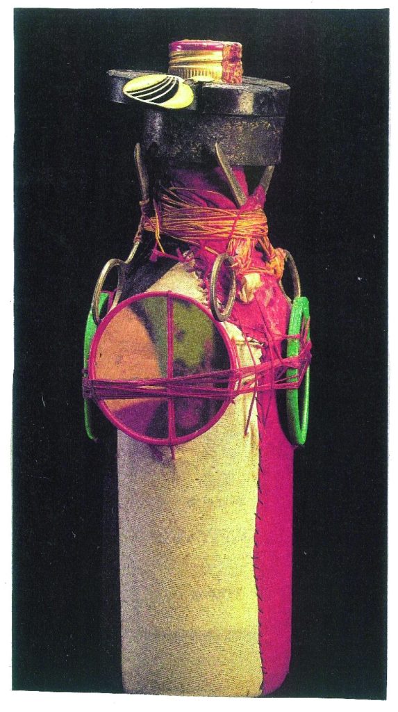 Color photograph of a bottle that contains a zombie, or part of a deceased person's soul, encased in cloth, sealed, and adorned with a mirror and a pair of scissors.