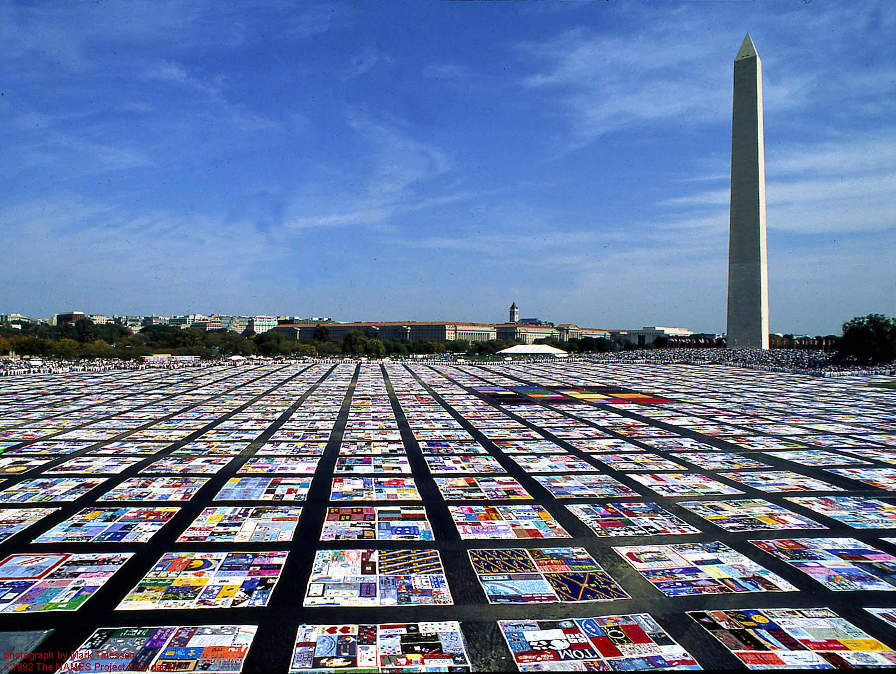 AIDS Quilt on the National Mall in Washington, D.C. Thousands of quilts stitched together in squares of four commemorating people who lost their lives to the horrific disease, with the Washington Monument in the background.