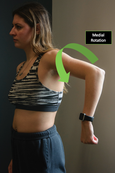 Person demonstrating medial rotation of the shoulder with a directional arrow.