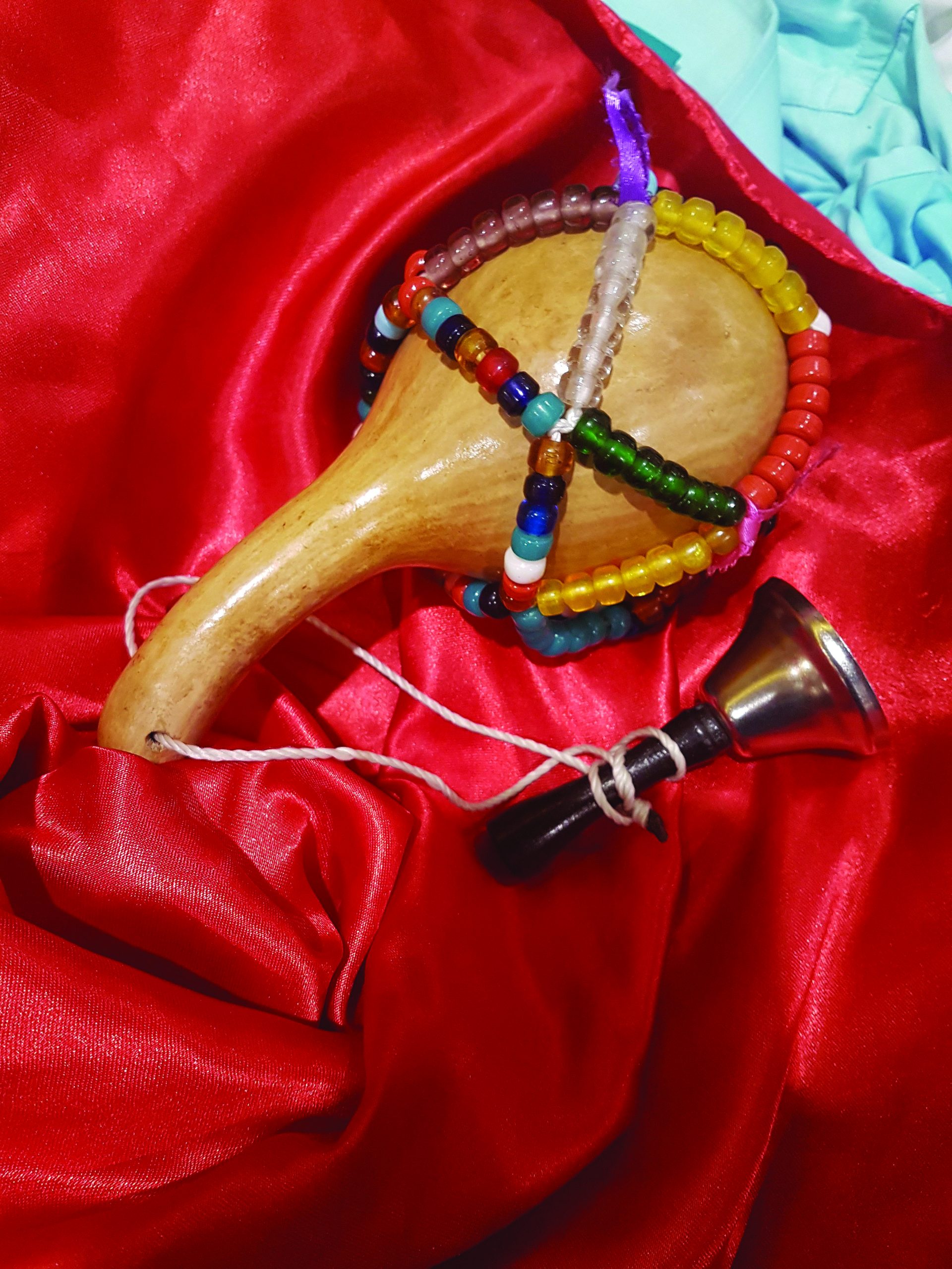 Color photograph of an asson, the sacred rattle of the Vodou priesthood, which is a gourd filled with serpent bones and covered with beads and attached to a bell.