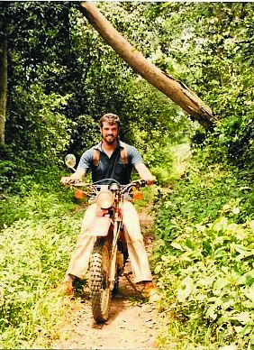 Color photo of the author on a two hundred fifty cc Yamaha Enduro, his iron horse, somewhere between Tandala and Bozene, Zaire, nineteen eighty-seven. Seated, helmetless, on a path in the jungle.
