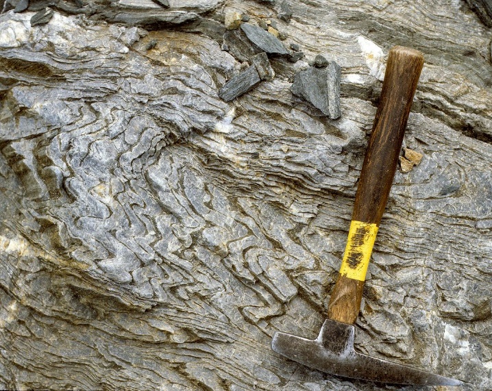 Folds in the Napeequa schist with a rock hammer for scale. Taken along Boulder Creek near Glacier Peak. Photograph credit: Tabor et al. 2009.