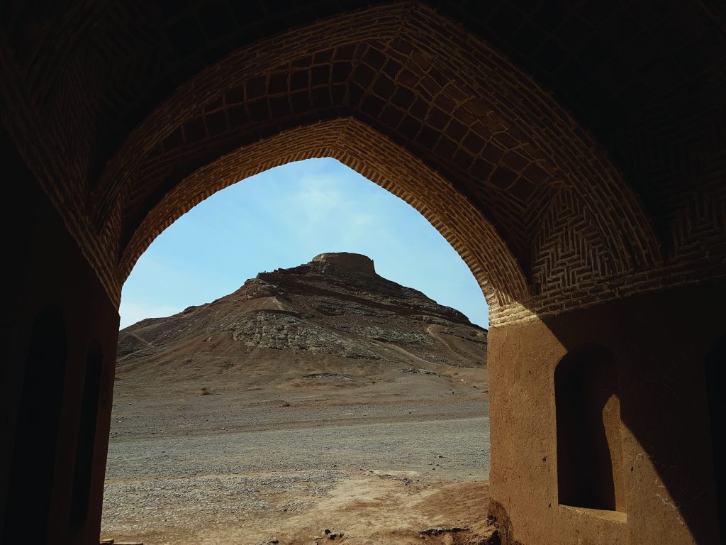 In Zoroastrianism the dead are placed atop hills, in arena-like structures that are called Towers of Silence, like the one pictured here, where the sun and vultures devour/decay their flesh. This spares the earth from the impurities of their rotting flesh.